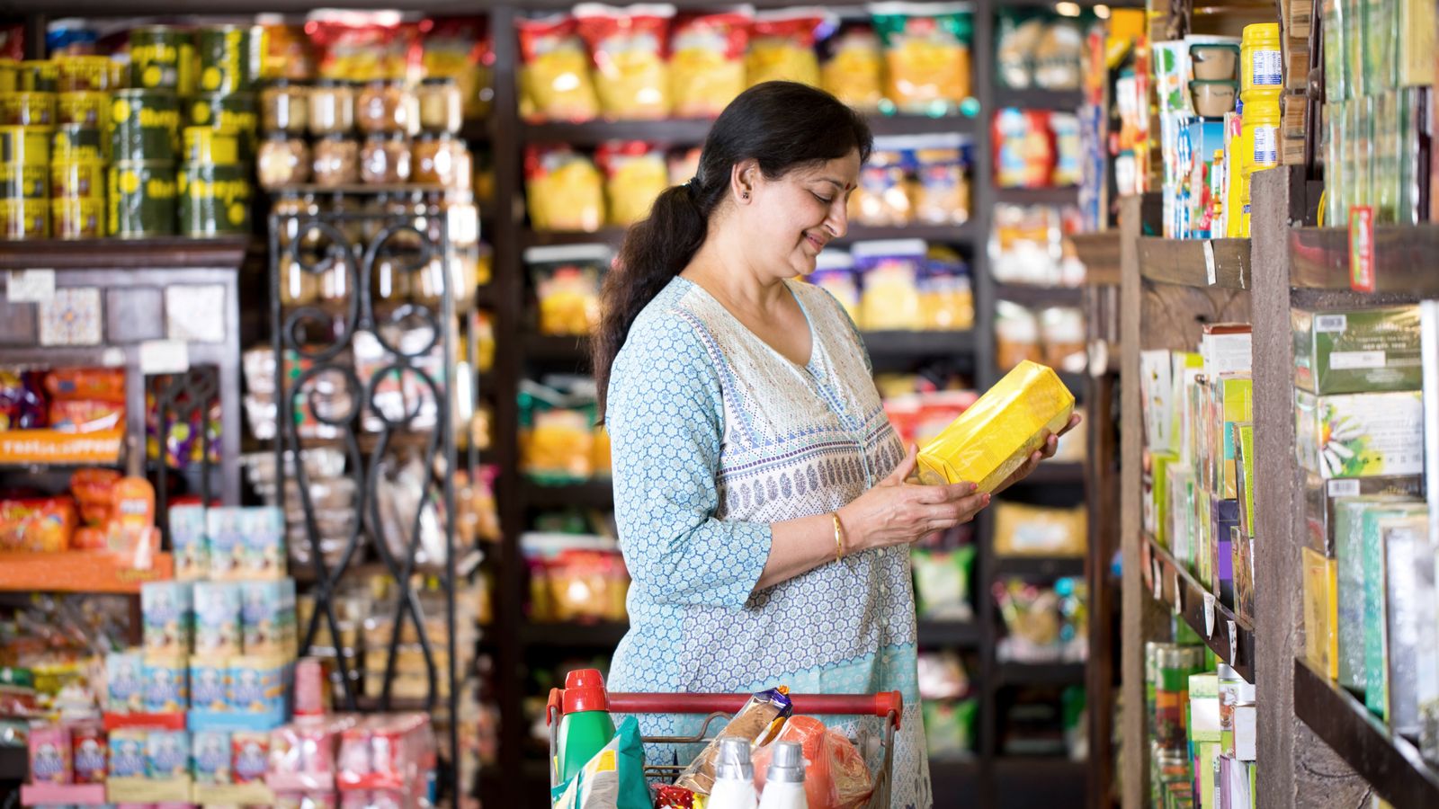 Shopper examining a product in a well-stocked Indian grocery store