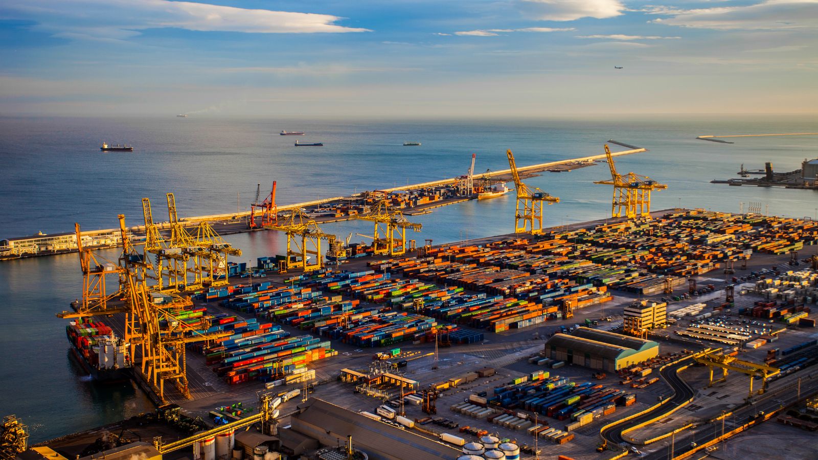 Container terminal at dusk — gantry cranes and stacked containers at a seaport